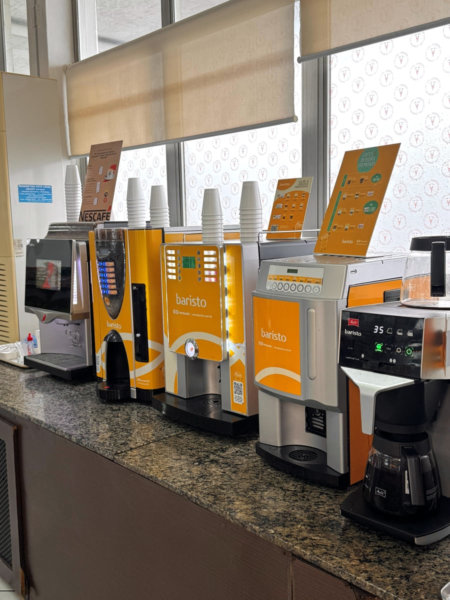 Estação de cafés da conveniência, com máquinas e copos à disposição